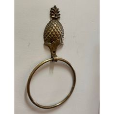 an antique brass pineapple towel ring hangs on a white wall