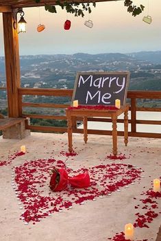 a sign that says marry me sitting on top of a bench with candles around it