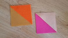 two pieces of felt sitting next to each other on a wooden table, one has an orange and the other is pink