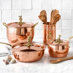 three copper pots with wooden spoons in them