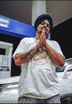 a man standing in front of a gas station with his hands clasped to his face