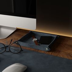 a desk with a computer monitor, keyboard and glasses on it next to a mouse pad