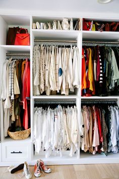 a closet filled with lots of different types of clothes and shoes on top of white shelves