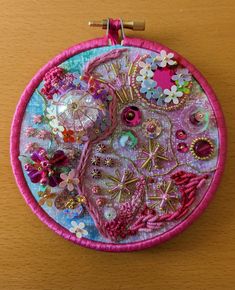 a close up of a circular object on a wooden surface with beads and flowers in it