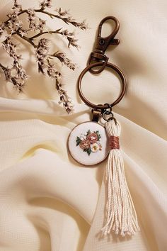 a keychain with a tassel hanging from it's side on a white fabric