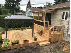 a wooden deck with a gazebo and potted plants on the bottom level next to it