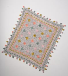 a crocheted square with pom - poms on it