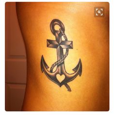 an anchor tattoo on the back of a woman's lower body, with a cross in the middle