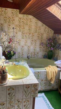 a bathroom with a green sink and bathtub next to a flowered wallpaper