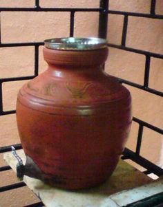 a large brown vase sitting on top of a piece of paper next to a brick wall