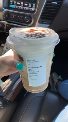 a cup of coffee sitting in the middle of a car with someone's hand holding it