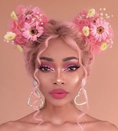 a woman with pink makeup and flowers in her hair is posing for the camera while wearing large earrings