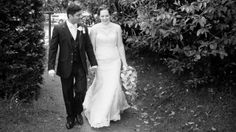 a bride and groom walking down a path in front of some bushes at their wedding