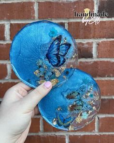 two blue plates with butterflies on them in front of a brick wall and someone's hand holding one