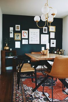 a dining room table with chairs and pictures on the wall behind it, along with an area rug