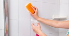 a woman is cleaning the wall with a sponge