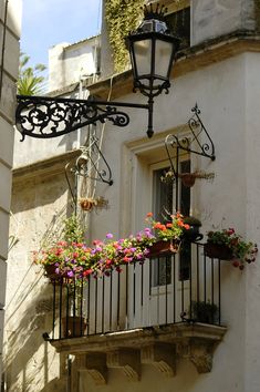 a balcony with flower boxes on the balconies and a street light above it