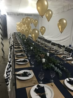 a long table set with plates, silverware and gold balloons