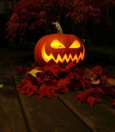 a carved pumpkin sitting on top of leaves