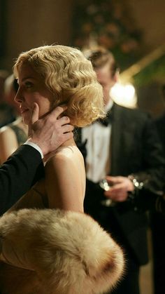 a man in a tuxedo hugs a woman's face while others look on