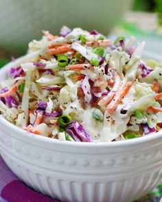 a white bowl filled with coleslaw on top of a purple and green table cloth