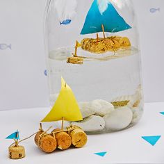 a glass jar filled with sand and small toy sailboat in it's bottom