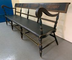 an old wooden bench sitting in front of a blue and white wall with writing on it