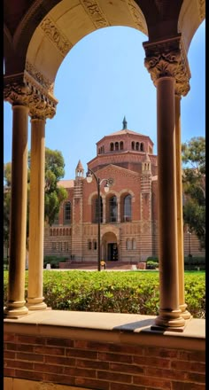 an old building with columns and arches in the foreground, surrounded by greenery