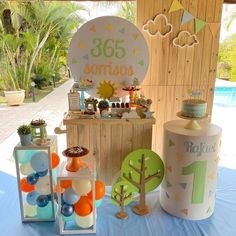 an outdoor birthday party with balloons, cake and decorations on a table next to a pool