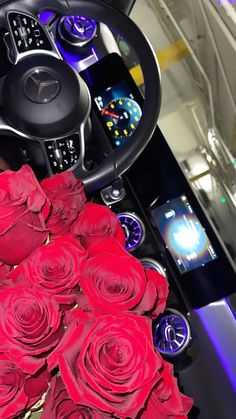 a bunch of red roses sitting on top of a table next to a steering wheel