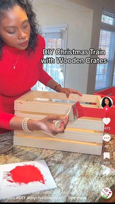 a woman is decorating wooden crates with red paint