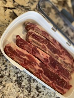 some raw meat in a white container on a counter