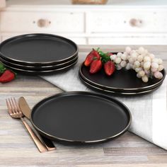 three black plates with gold rims and strawberries on the plate next to each other