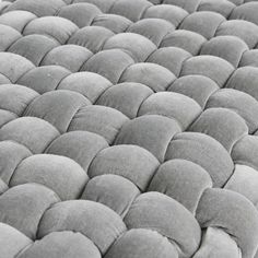 a close up view of the back end of a bed with grey pillows on it