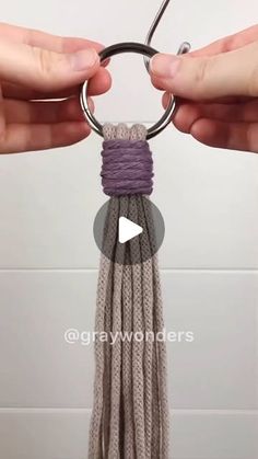 two hands holding a keychain that is made out of yarn and metal rings