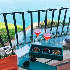 two glasses of wine on a balcony overlooking the ocean