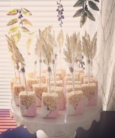 a cake with marshmallows and feathers on it sitting on a table next to a window