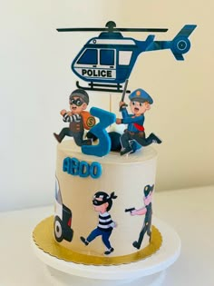 a police cake is decorated with cartoon figures and a helicopter on top that says ardo