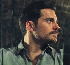 a man in a green shirt looking off into the distance