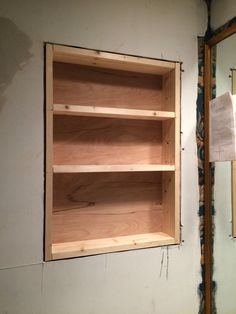 a wooden shelf sitting in the corner of a room next to a mirror and wall