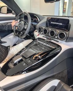 a man sitting in the driver's seat of a car with his hands on the steering wheel