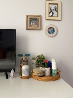 a flat screen tv sitting on top of a white table next to a potted plant