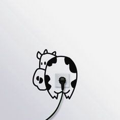 a black and white cow is plugged in to a wall outlet with the light on