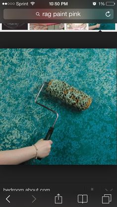 a person holding a paint roller on top of a blue carpet with green flecks