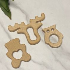 three wooden animal shaped objects on a white tablecloth next to a green leafy plant