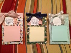 three small cards with bows on them sitting on a striped bed sheet in front of a pillow