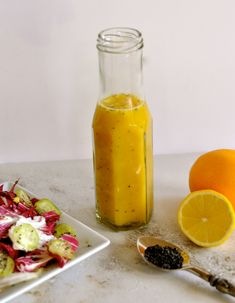 there is a glass bottle with some liquid next to it and an orange on the table