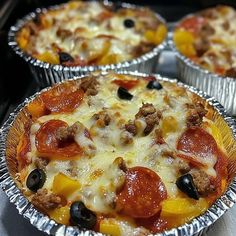 three pizza pies sitting in tin foil pans on top of a stovetop