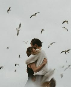 two people embracing each other while birds fly overhead