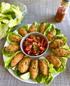 a white plate topped with lettuce covered in meat patties and tomato salad